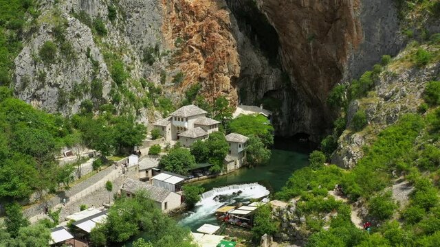 Aerial: Tourists Exploring Vrelo Bune During Vacation, Drone Flying Over Green Trees - Blagaj, Bosnia and Herzegovina