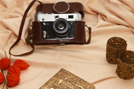 Flatlay. Film camera in case, notebook, fisalis and candlesticks lie on a beige background.