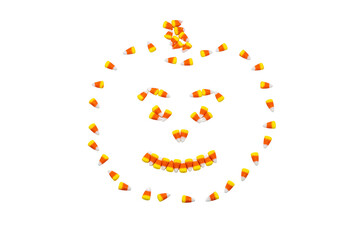 Candy corn arranged in the shape of a carved halloween pumpkin isolated on a white background