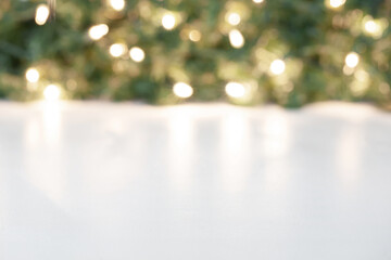 Blurred Christmas tree branch background with sparkling Christmas lights. White table background mockup.