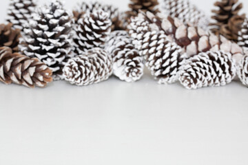 White table background mockup with snow covered pine cones as decoration.