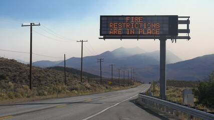 An electronic sign along a highway warns that fire restrictions are in place, as the Caldor Fire rages in the background near Lake Tahoe, California.
