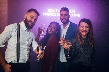 Friends dancing on a party in a club while drinking champagne