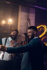 Happy group of friends celebrate New Year's Eve and taking selfie with a smartphone