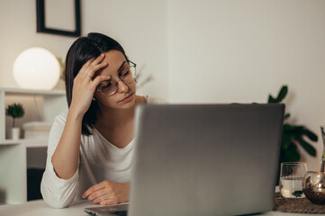 Woman feeling tired and stressed while using a laptop and working from home