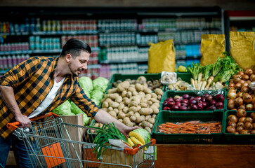 Young handsome man in a supermarket grocery shopping