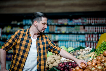 Young handsome man in a supermarket grocery shopping