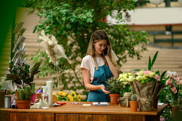 Florist talking with client on the smartphone and taking an order in a flower shop