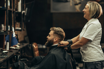 Man is being prepared for a haircut while sitting in chair at barbershop