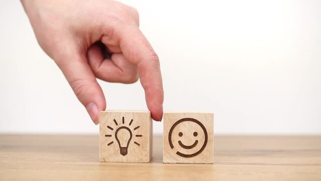 New creative idea and business strategy concept. Hand arranging wooden block with light bulb and smiley face icon