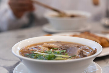 Delicious bowl of pho tai, rich broth, Vietnamese dish, soup, rice noodles.