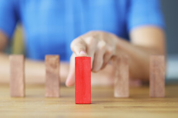Female hand choosing red block among wooden closeup