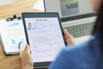 Woman employer holding digital tablet in hands with resume of man for employment closeup