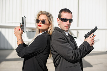 Professional female and male security spy agents posing with guns