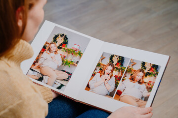 top view. woman flips through pages of photobook from photo shoot pregnancy