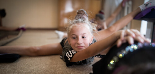 Girl gymnast stretching on training in sports camp