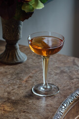 still life with a bouquet of flowers and whiskey cocktail in hollow stem coupe glass