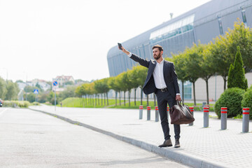 Fototapeta premium Male businessman can not catch free taxi at busy time. business man does not successfully stop a taxi on a city street. can't catch a car on the road waving his hand. standing on the sidewalk outside