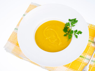 White plate with thick pumpkin cream soup. Studio Photo.