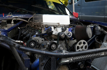 Sports car engine with turbine. An open race car hood on a pit stop while racing on a race track....