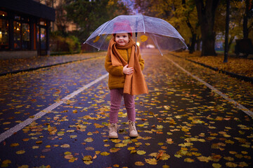 happy baby girl with umbrella on the walk in the autumn city, cozy warm clothing