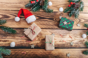 Gifts, Santa Claus hat, fir branches and berries, on a wooden texture background. View from above.