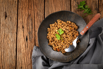 Ground beef in dark plate on the table.