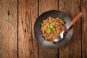 Ground beef in dark plate on the table.