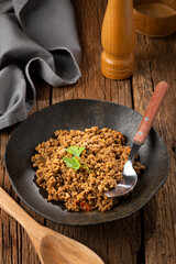 Ground beef in dark plate on the table.