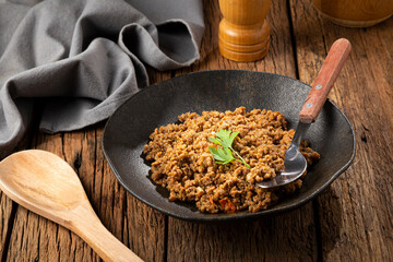 Ground beef in dark plate on the table.