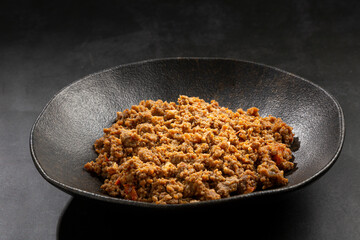 Ground beef in dark plate on the table.