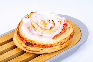 Sweet bun with raisins and white sugar icing. Studio Photo.