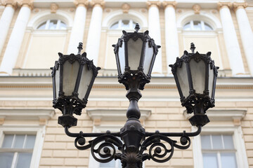 Fototapeta na wymiar Black vintage street lamp on the beige building background