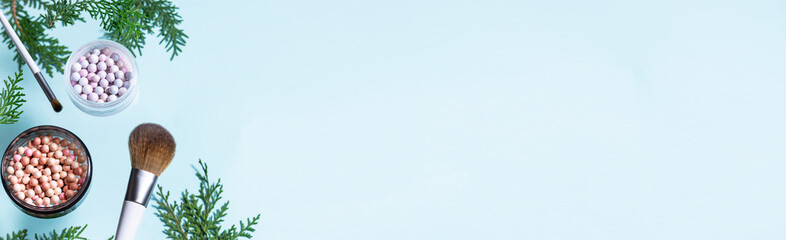 Decorative cosmetic set and make up brushes with fir tree branches on light blue background long banner format. Christmas cosmetic sale and promo banner.