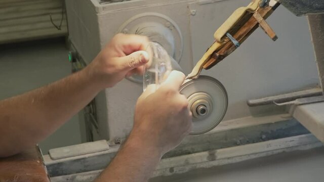 Close up man doing a glass carving. Manufacturing of crystal vases