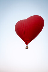 A hot air balloon flies over a green field. Composition of nature on a background of blue sky.