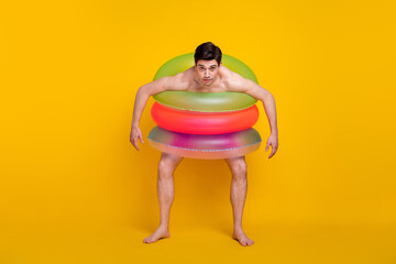 Full body photo of young man air circle ring float fooling bathing ocean isolated over yellow color background
