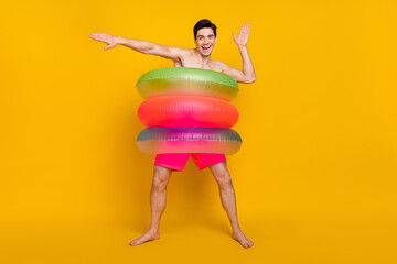 Full body photo of young man happy positive smile have fun journey circle swim isolated over yellow color background