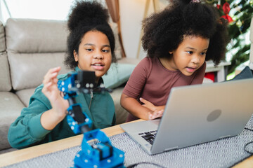 Two African American girls learned robot arms with a program computer. Innovative technology mechanical for Assistive Technology