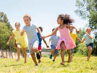 Group of happy kids running in race in the street and laughing in park