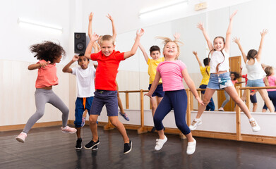 Fototapeta na wymiar Happy kids of different nationalities and ages jumping during class in dance school