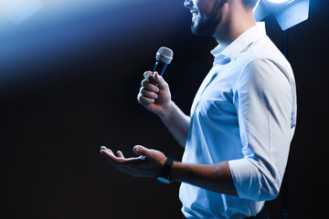 Motivational speaker with microphone performing on stage, closeup. Space for text - obrazy, fototapety, plakaty