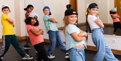 Multiethnic group of children in casual wear training hip hop movements in dance class with female...