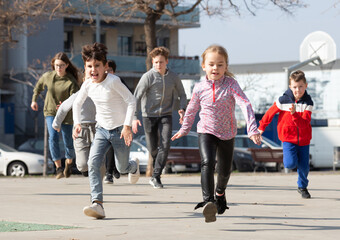 Obraz na płótnie Canvas Large group of playful children running together at urban landscape