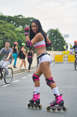 Fototapeta premium Latina woman skating in the street. With protection on elbows and knees post-pandemia.