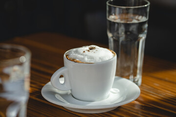 Cup of coffee on the wooden table with white milk cream