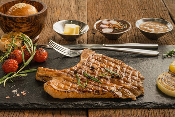 pork chop steak on stone plate with sauce and butter and bread