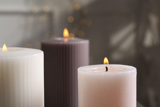 Different burning candles on blurred background, closeup