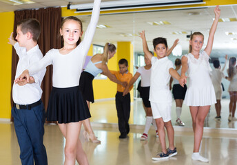 Children are dancing twist in pairs indoors.