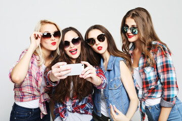 Obraz premium four happy teenage girls with smartphone taking selfie